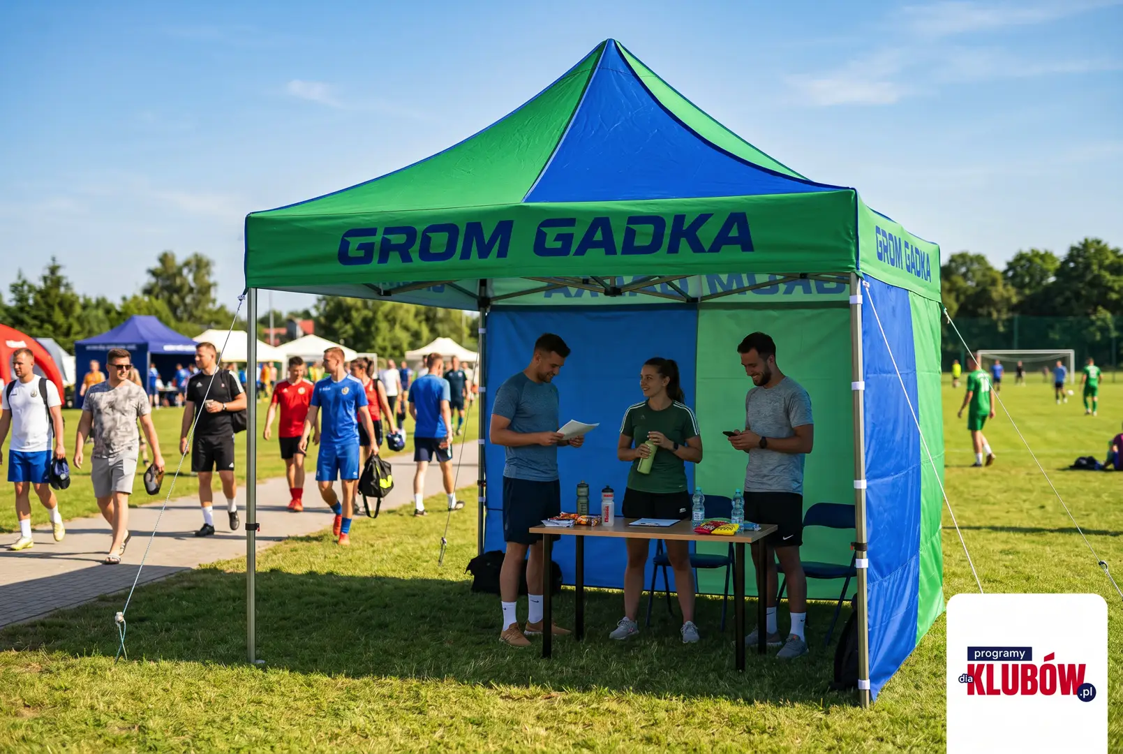 Czerwony namiot reklamowy klubu Grom Gadka na trawie podczas festynu sportowego